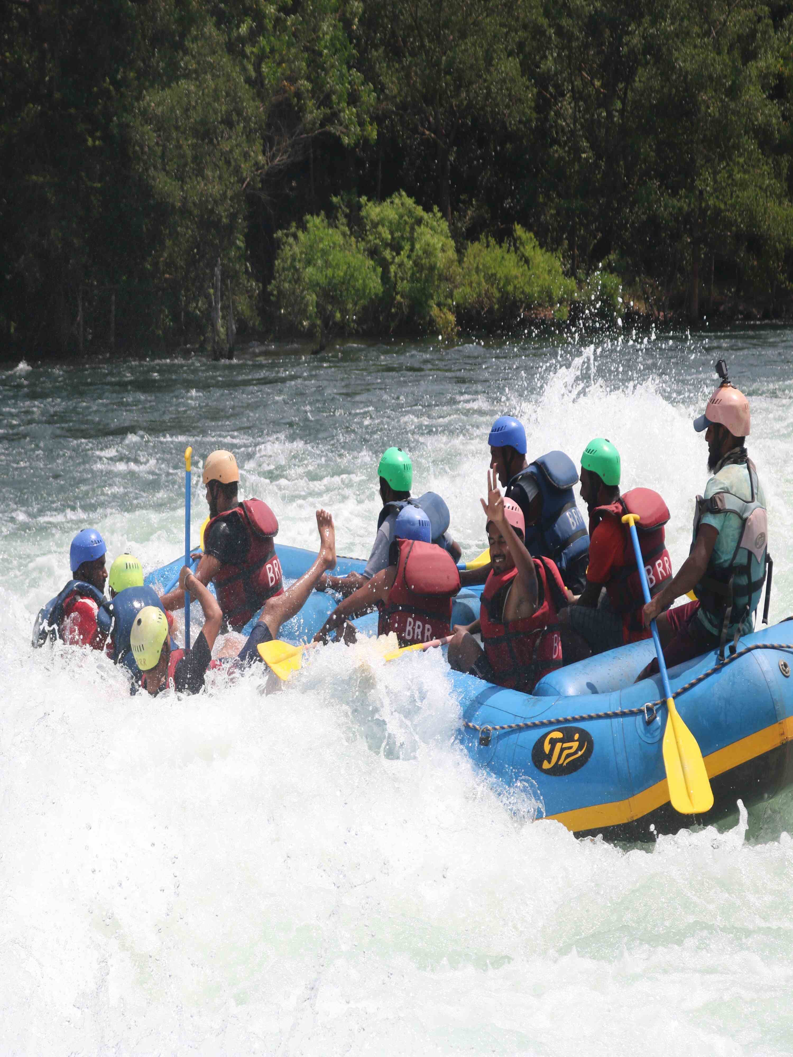 Group of friends in a raft navigating the rapids of the Kali River during rafting in Dandeli