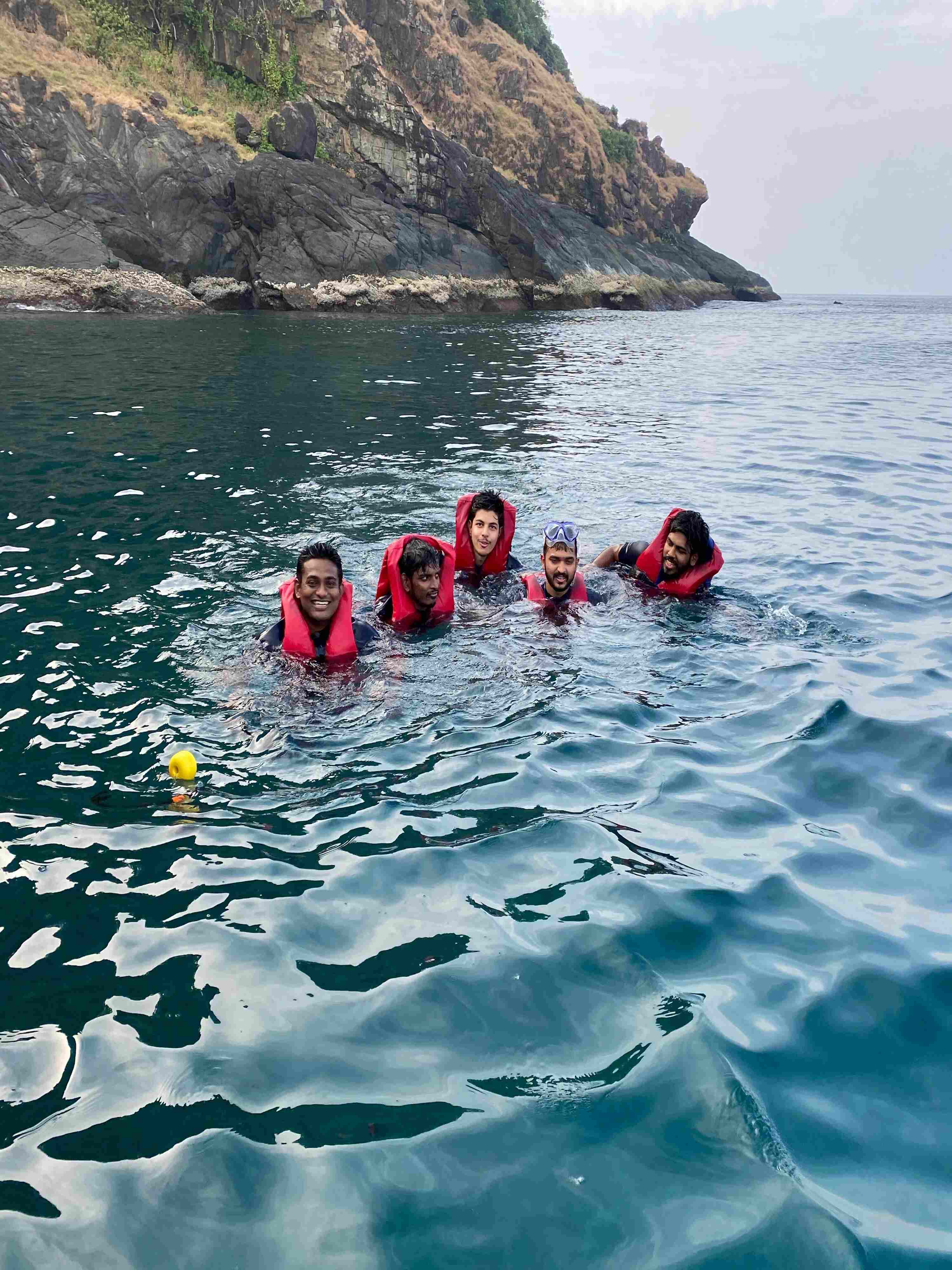 Scuba divers in gear preparing to descend into the water at Netrani Island for underwater exploration