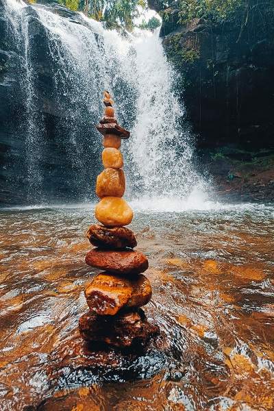 Visitors stacking rocks by the waterfall as a mark of their adventure at Soormane Falls