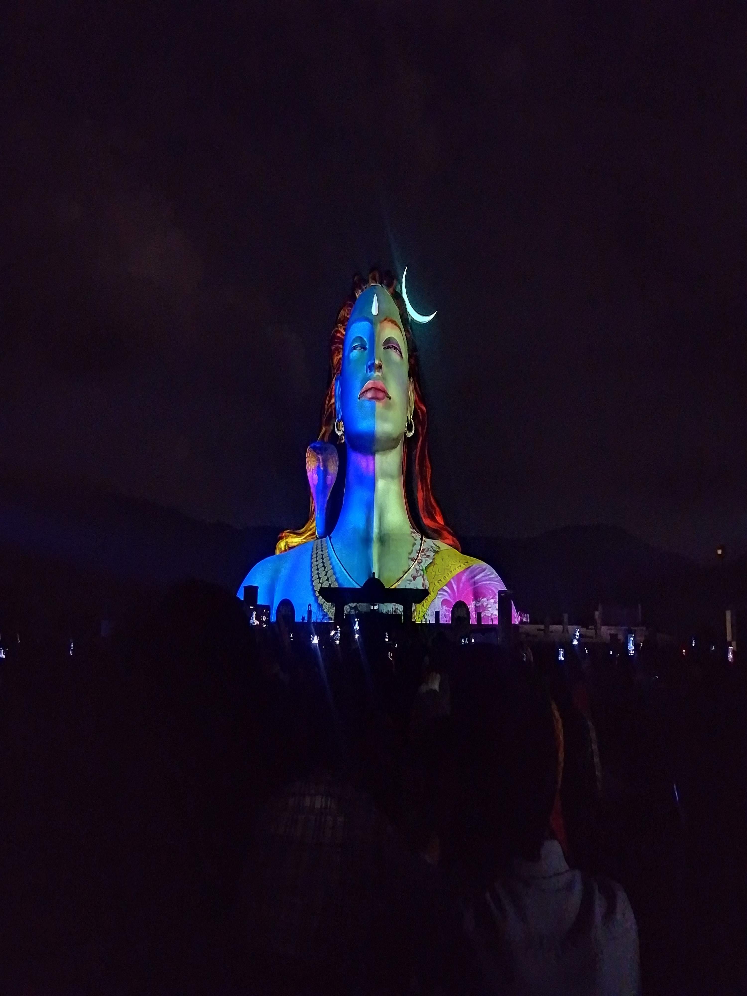 Evening light show projecting colorful animations of Lord Shiva on the Adiyogi statue at Isha Foundation